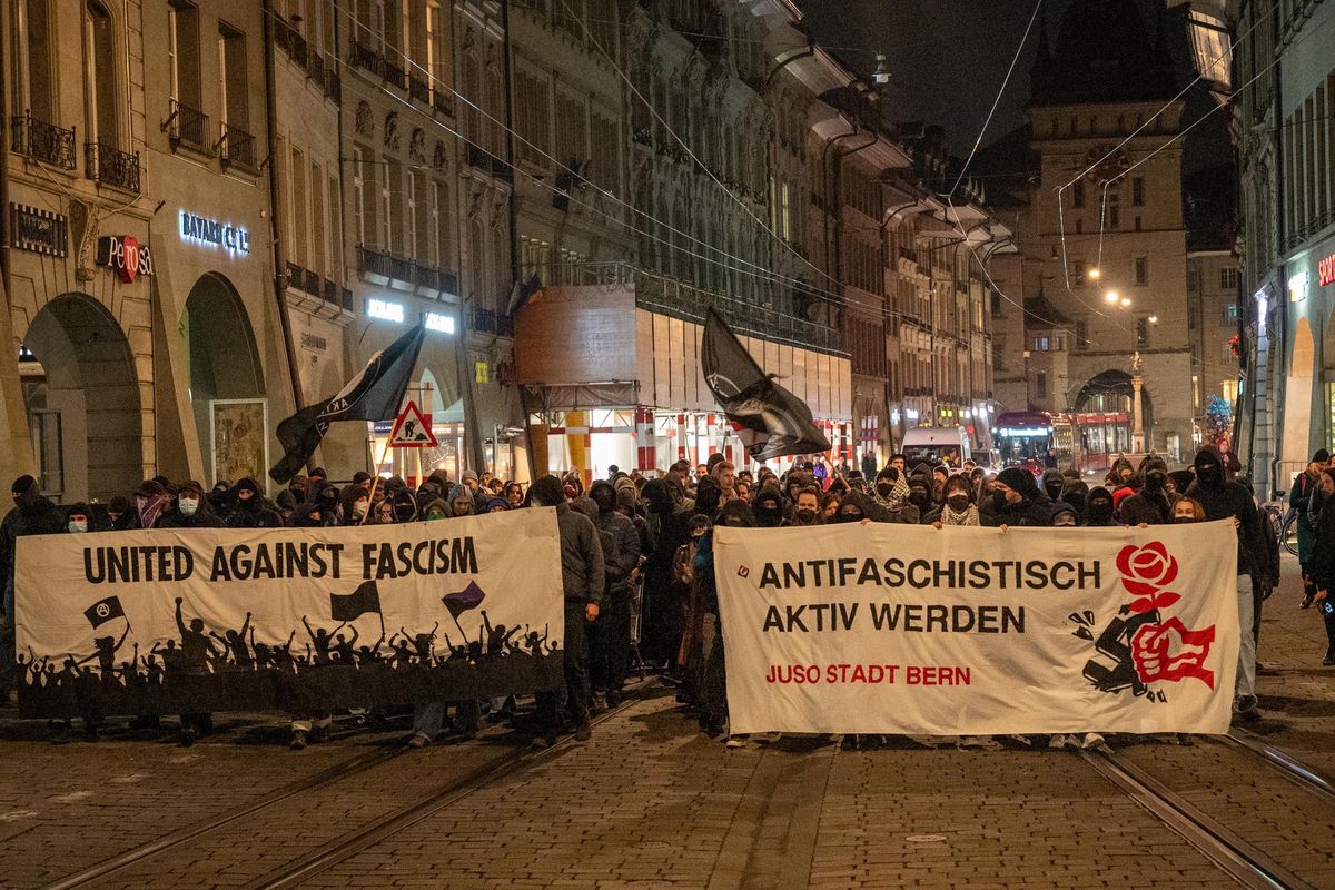 Eine nächtliche Demonstration in einer Strassenpassage mit Transparenten 'United Against Fascism' und 'Antifaschistisch aktiv werden' in Bern.