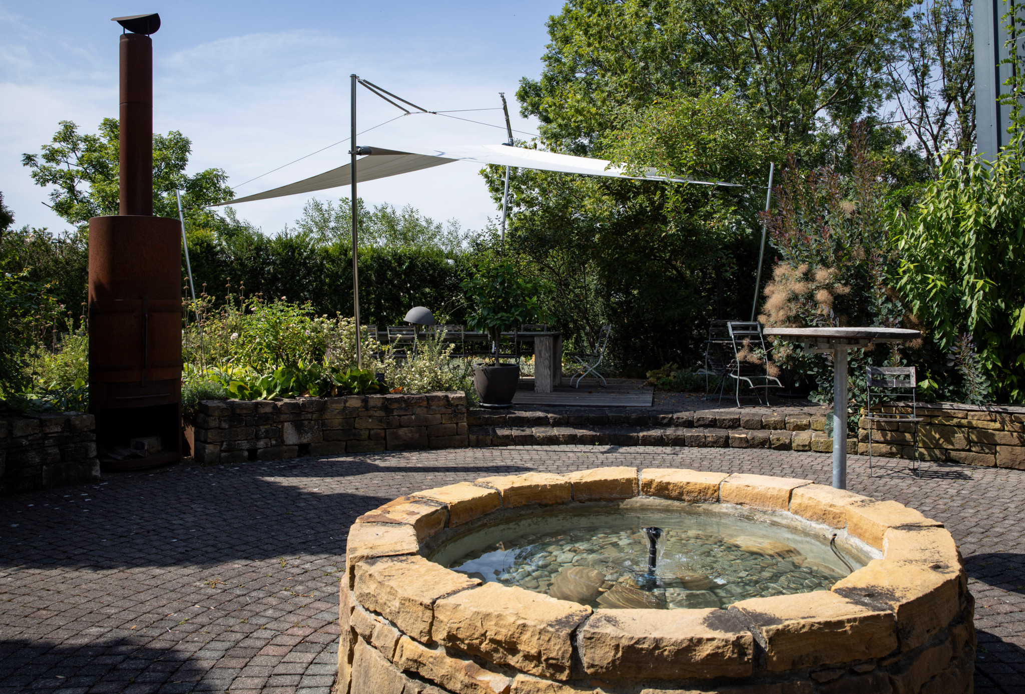 Dachbiotop der Firma Contec in Uetendorf mit Themenweg, schattenspendender Pergola und Steinbrunnen.