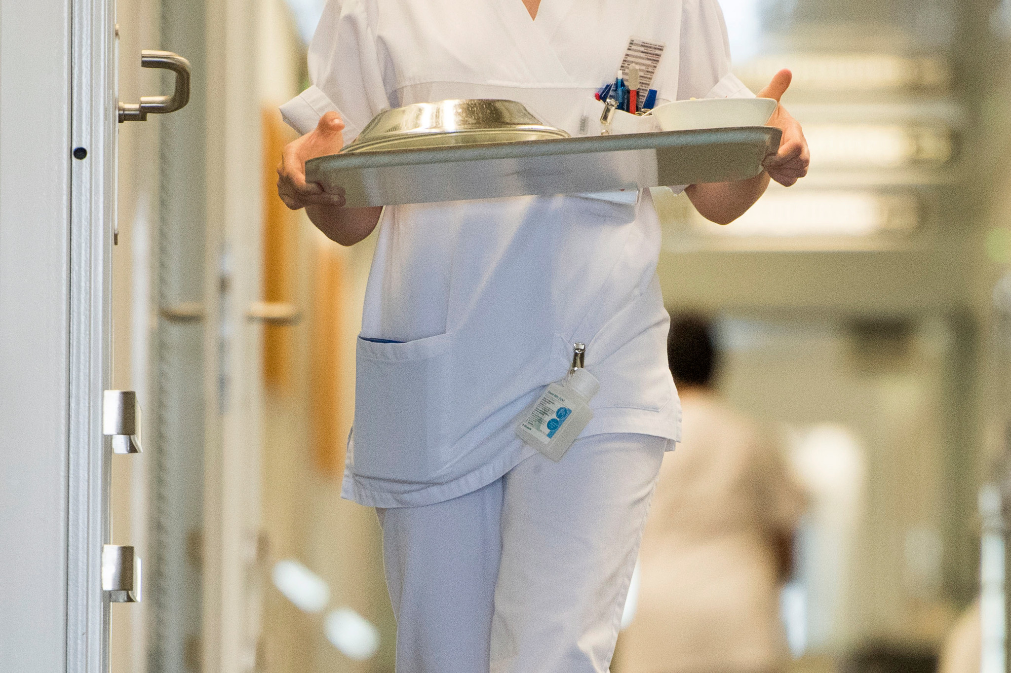 Eine Pflegerin in weisser Uniform bringt ein Tablett mit Essen auf die Privat-Abteilung im achten Stock des Kantonsspitals Winterthur.