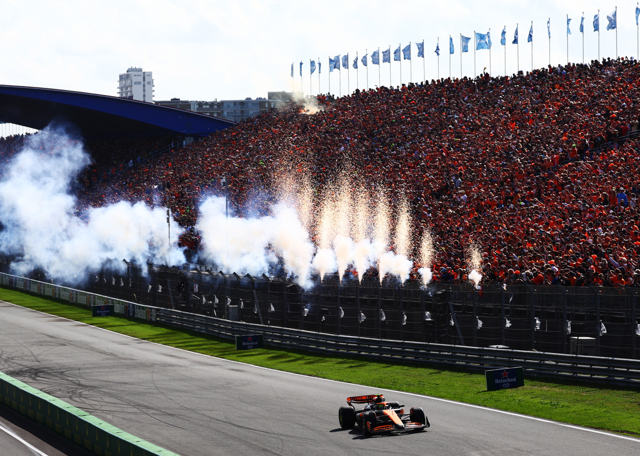 Zwei Formel-1-Autos in einem Rennen auf einer Kurve, mit einem Auto in orange-schwarzen Farben vorne und einem Auto in dunklen Farben dicht dahinter. Im Hintergrund Salesforce-Werbebanner entlang der Strecke.