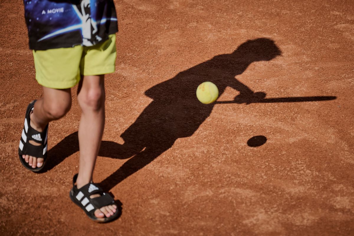 Un jeune enfant joue au tennis sur un court en terre battue pendant les vacances d'été au Tennis Club de Montchoisi à Lausanne, le 17 juillet 2024.