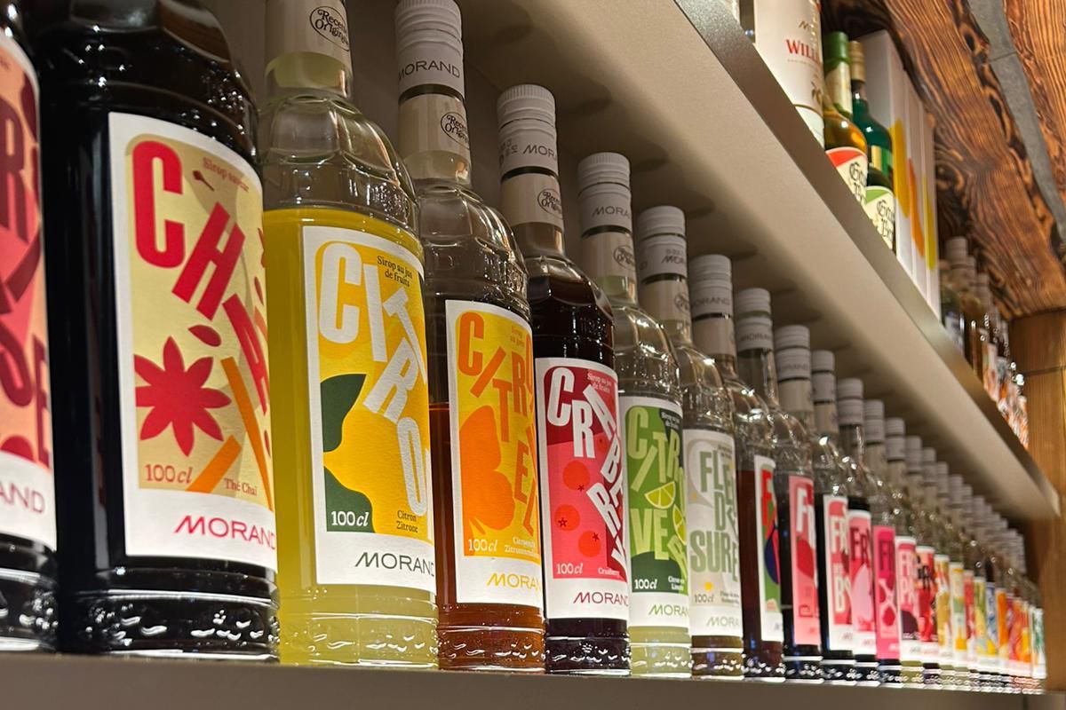 Bouteilles colorées d’apéritifs alignées sur des étagères dans un magasin.