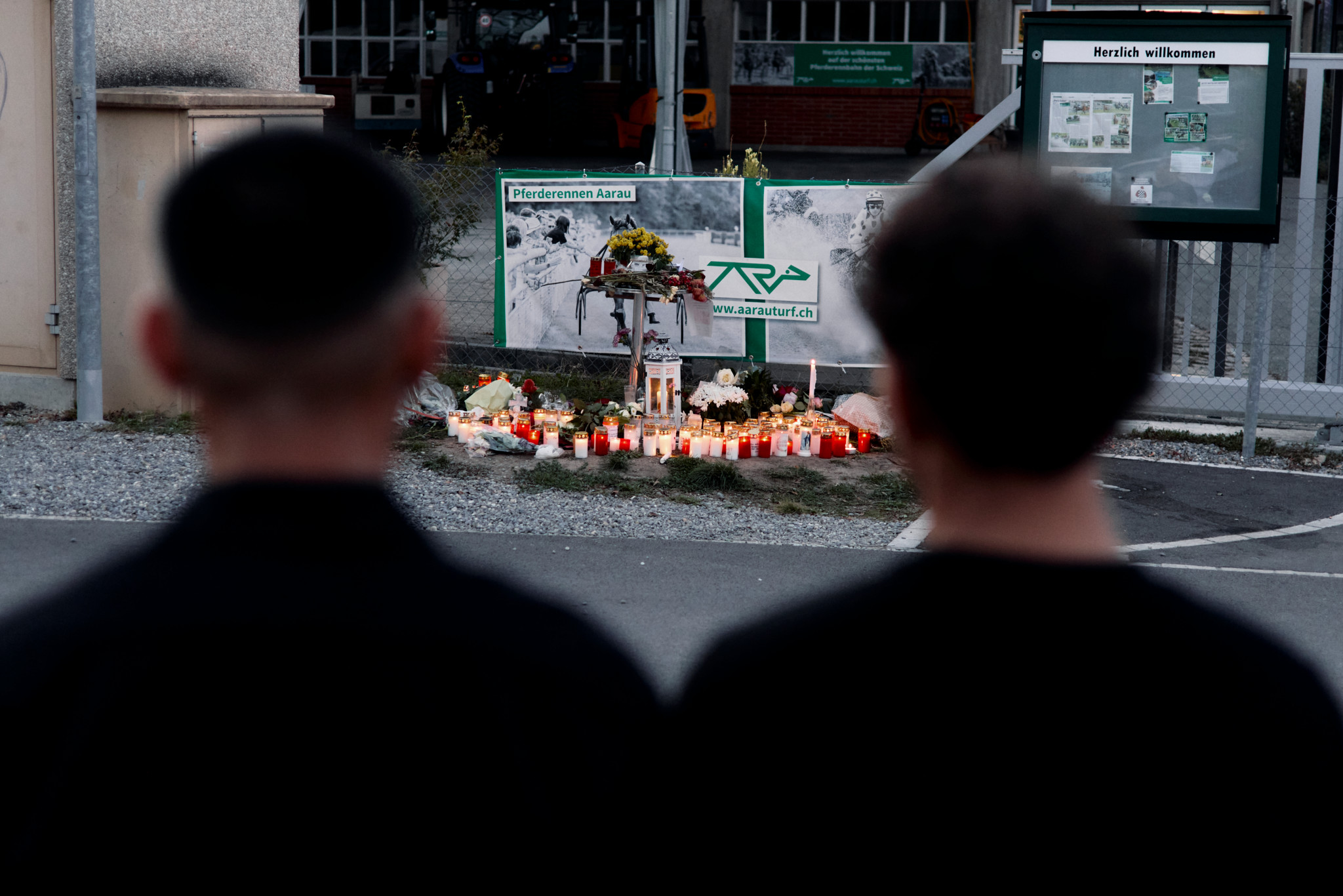 Zwei Personen stehen bei einer Gedenkstätte mit Kerzen und Blumen für die Opfer des Attentats beim Rave in Aarau.