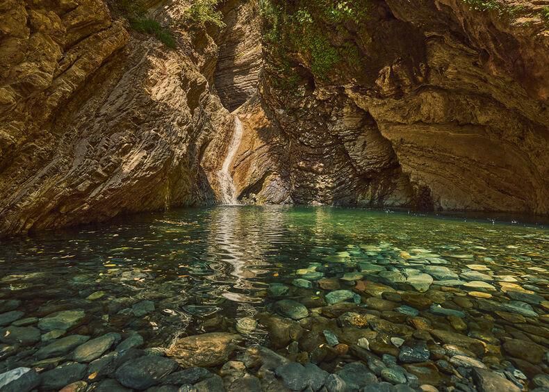 Piscine naturelle entourée de parois rocheuses avec de l’eau claire et lumineuse.