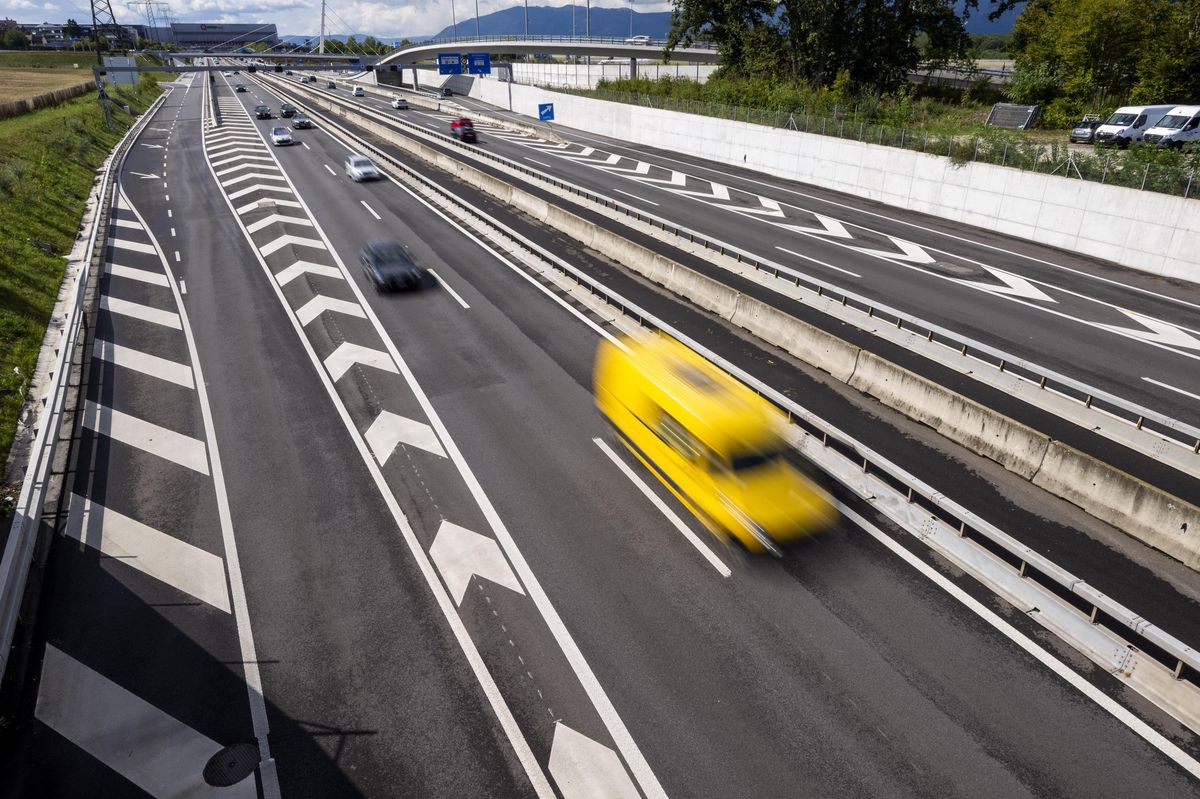 Vue aérienne de l'autoroute A1 près de Grand-Saconnex, montrant plusieurs véhicules, dont un véhicule jaune flou, à Genève.