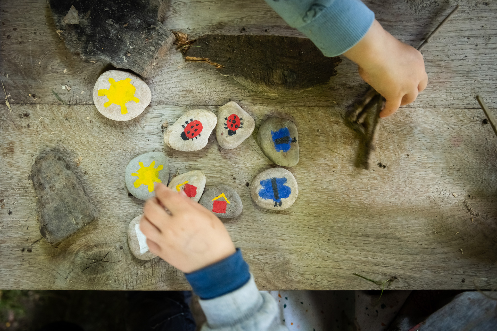 Kinder bemalen Holzscheiben mit bunten Motiven wie Marienkäfern und Sternen in der Natur-Kita Baroudeurs du caillou in Saint-Triphon. Kinder bemalen Holzscheiben mit bunten Motiven wie Marienkäfern und Sternen in der Natur-Kita Baroudeurs du caillou in Saint-Triphon.