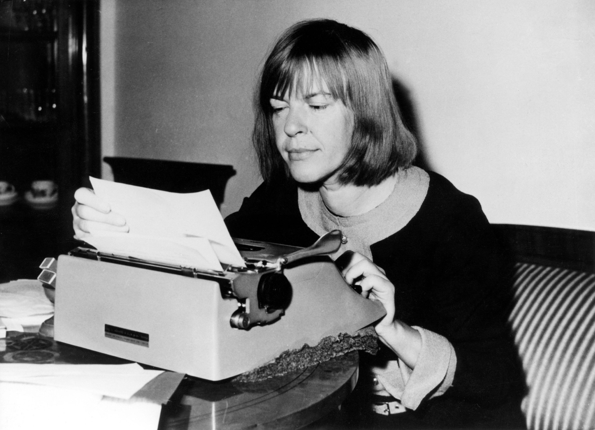 Ingeborg Bachmann, österreichische Schriftstellerin, an der Schreibmaschine in ihrer Berliner Wohnung, 1964. Schwarz-Weiss-Aufnahme.