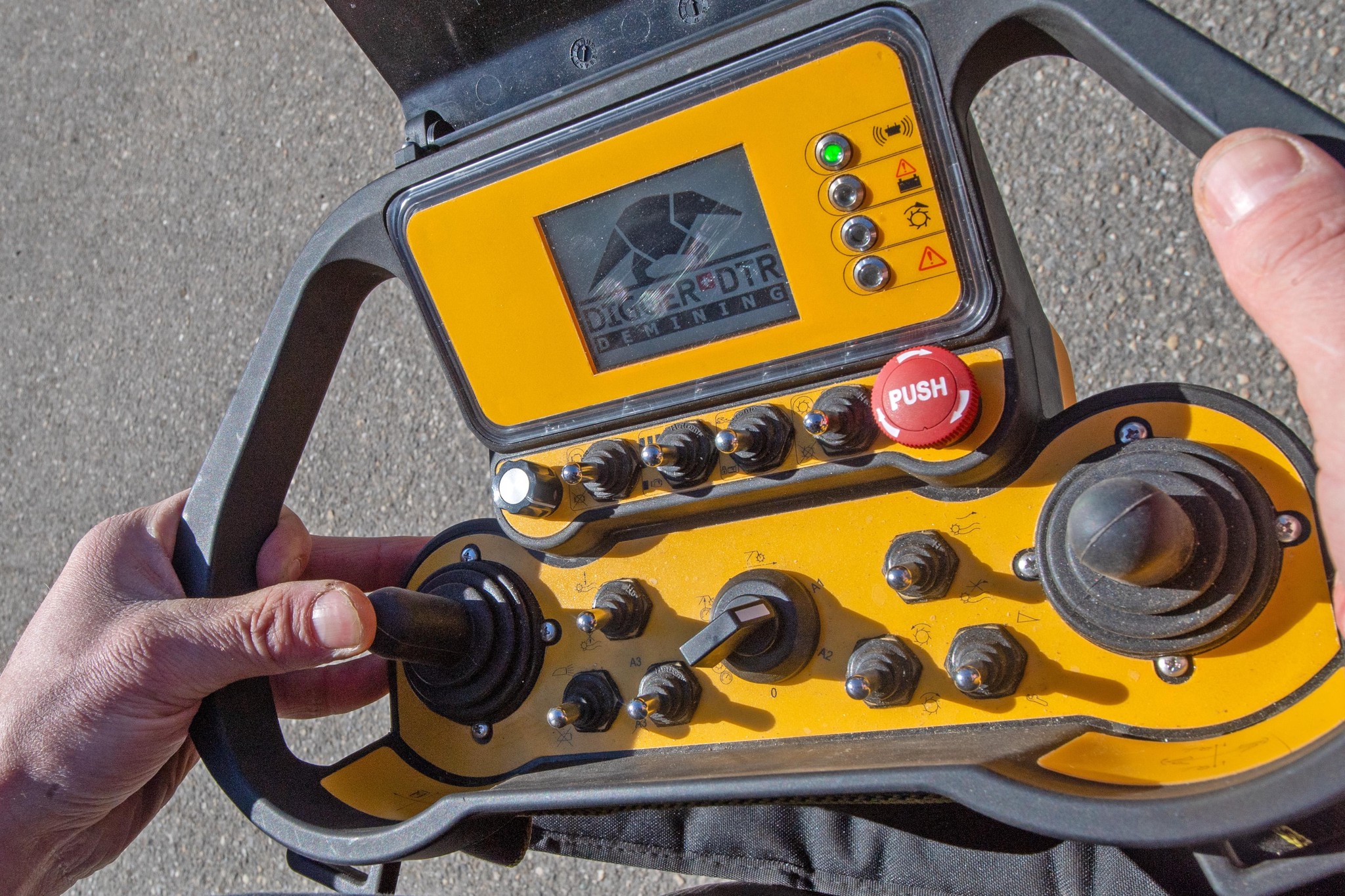 Nahaufnahme eines Steuerungsgeräts für einen Minenräumer der Stiftung Digger, mit gelbem Gehäuse und verschiedenen Knöpfen und Hebeln.
