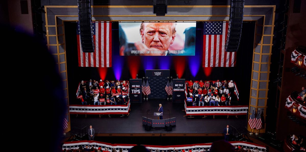 Rassemblement de campagne de Donald Trump au Cobb Energy Performing Arts Centre à Atlanta, avec des drapeaux américains en fond et une foule de partisans.