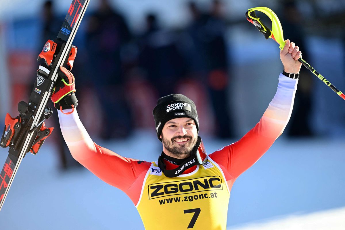 Loic Meillard, skieur suisse, célèbre sa deuxième place lors du slalom masculin de la Coupe du Monde FIS à Alta Badia, tenant ses skis en l’air, le 23 décembre 2024.