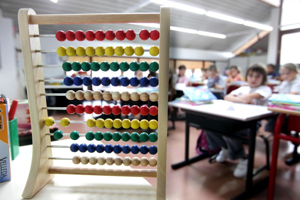 Des élèves sont en classe le jour de la rentrée scolaire au groupe scolaire public du 'Quartier des écoles', avec un boulier coloré au premier plan. Photo Lucien Fortunati