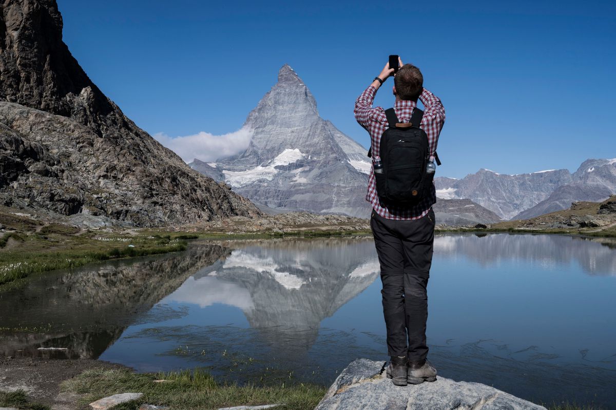Ein Tourist fotografiert das Matterhorn und seine Spiegelung im Riffelsee, aufgenommen am Montag, 25. Juli 2022 oberhalb von Zermatt. (KEYSTONE/Christian Beutler)