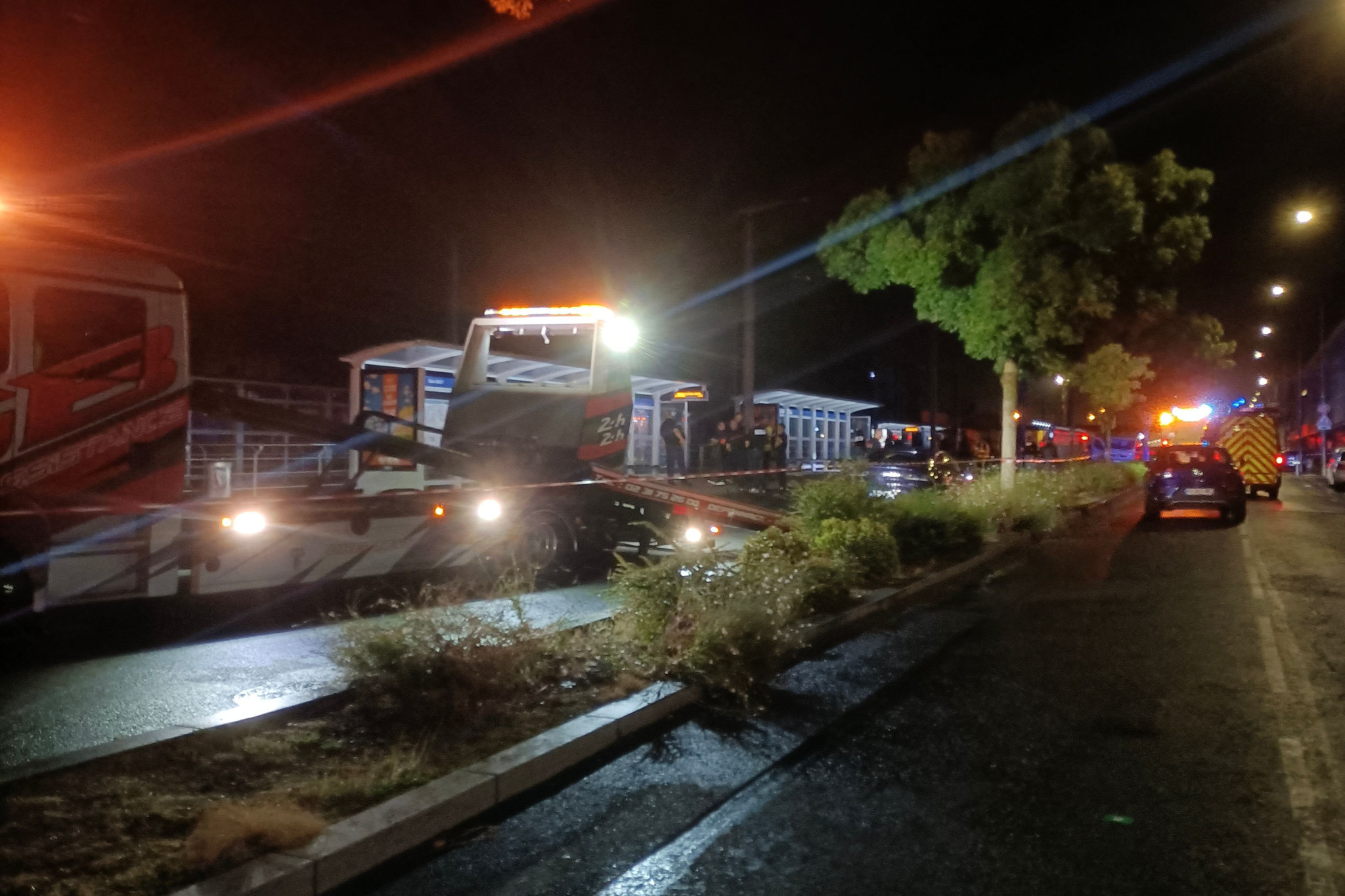 Polizei untersucht nächtliche Unfallstelle in Caen, wo ein Auto in eine Menschengruppe fuhr. Einsatzfahrzeuge beleuchten die Strasse.