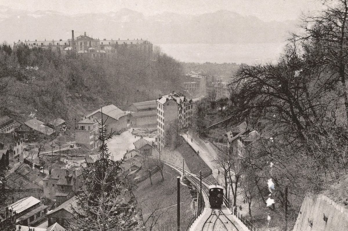 Vue ancienne de Lausanne avec funiculaire, bâtiments historiques et montagnes en arrière-plan.