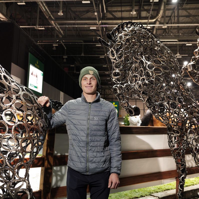 Le cavalier Guillaume Gillioz au Concours Hippique International de Genève 2024, posant près de sculptures de chevaux.