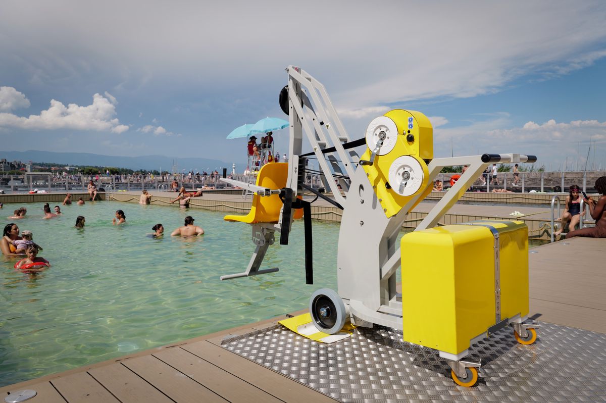 Le nouveau dispositif de baignade pour personnes à mobilité réduite aux Bains du Jet d'eau à Genève, installé près de la piscine avec des baigneurs en arrière-plan, le 12 août 2024.