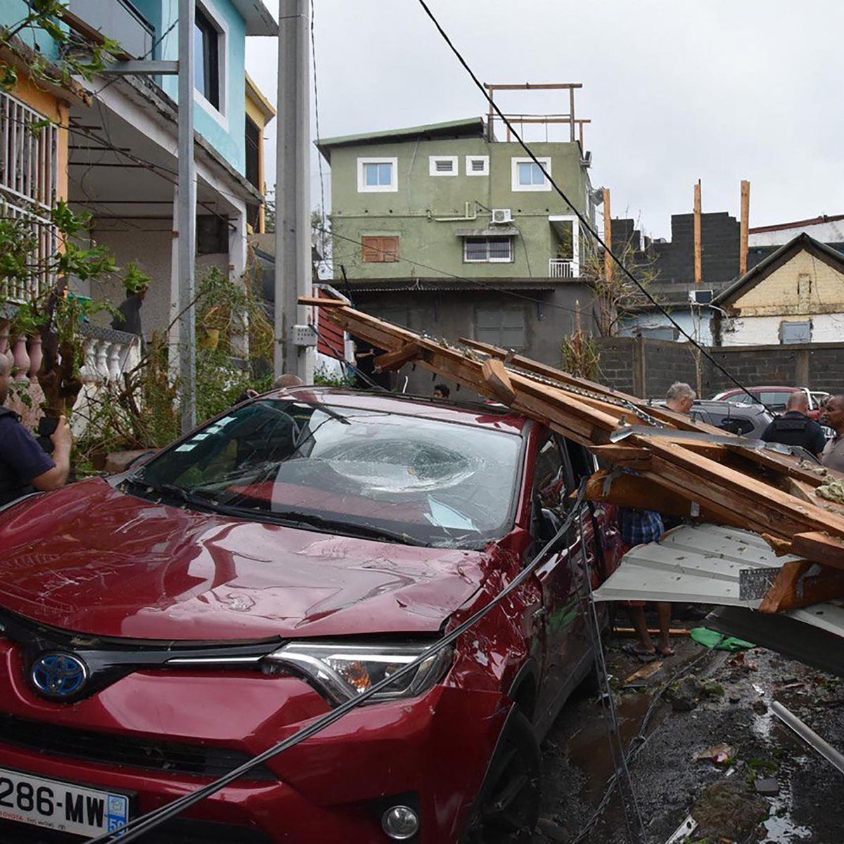 Dégâts causés par le cyclone Chido à Mayotte, avec des débris sur des voitures et des maisons endommagées dans une rue, le 16 décembre 2024.