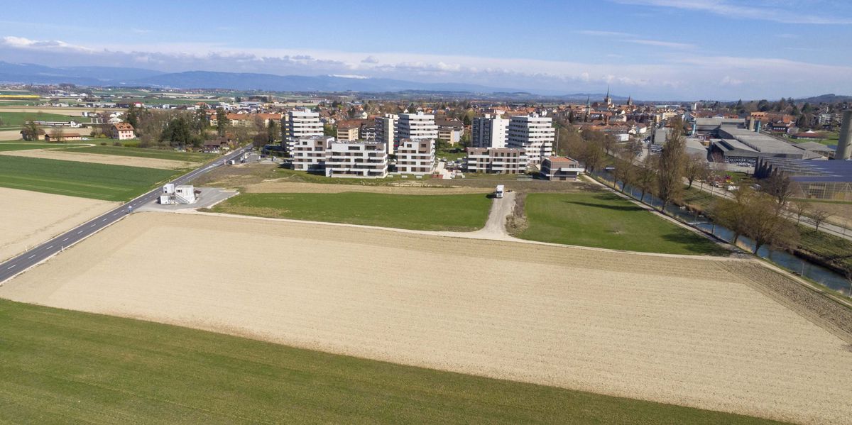 Vue aérienne du quartier des Rives de la Broye à Payerne, montrant des immeubles modernes entourés de champs le 25 février 2019.