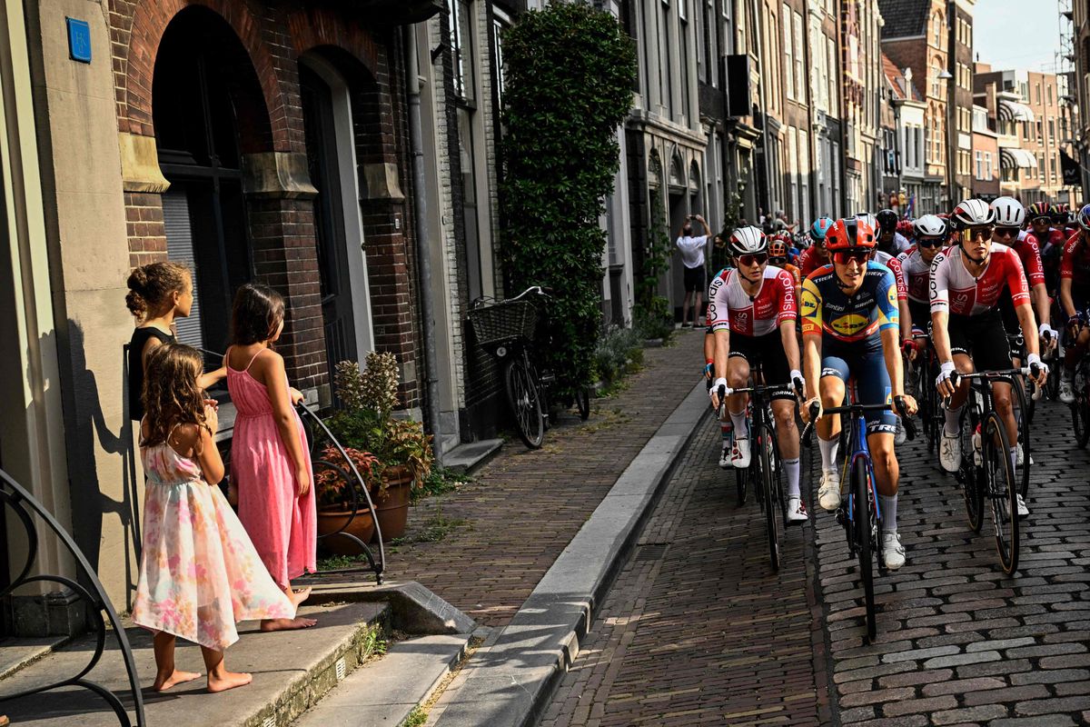 Le peloton concourt lors de la 2ème étape du Tour de France féminin 2024 entre Dordrecht et Rotterdam, avec des enfants regardant la course depuis un trottoir.