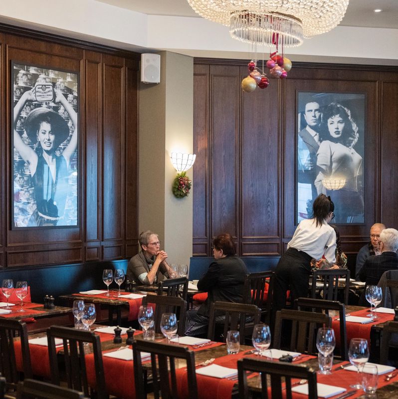 Gäste sitzen an einem Tisch im Restaurant Commercio mit Fotos von Sofia Loren an der Wand.