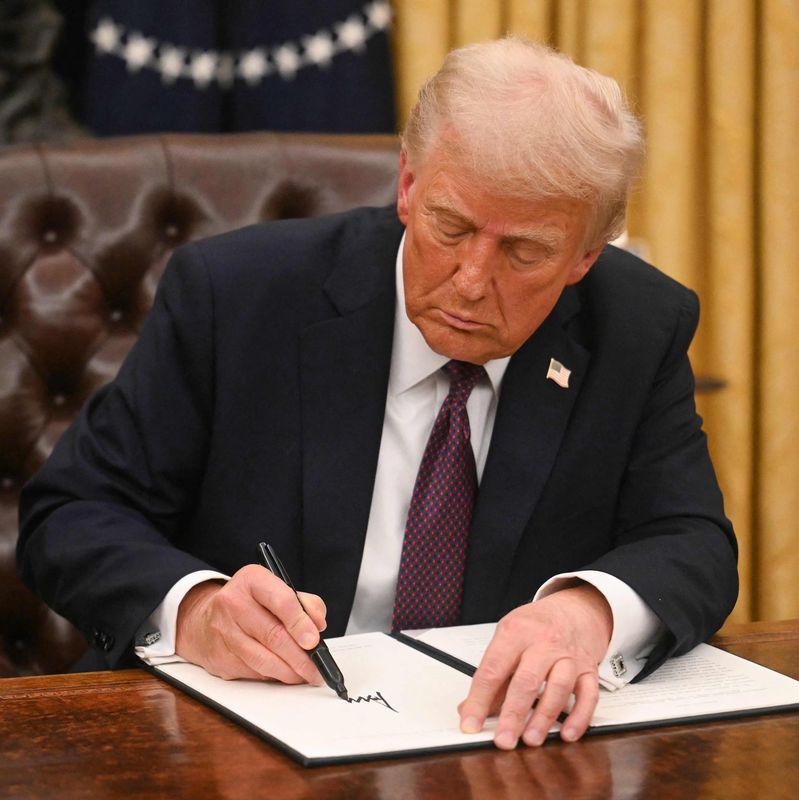 Un homme signe un ordre exécutif dans le bureau ovale de la Maison-Blanche à Washington, DC, le 20 janvier 2025.