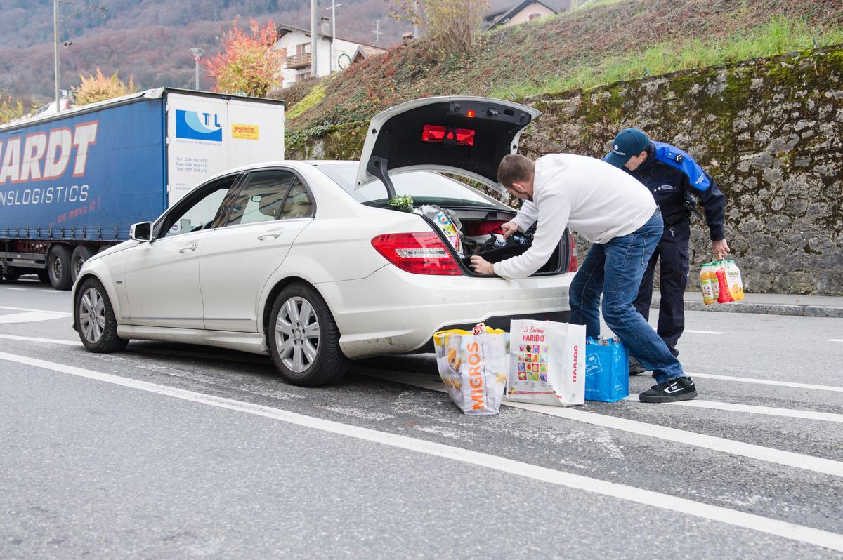 Contrôle à la frontière à Saint-Gingolph, le 3 décembre 2014, concernant les nouveaux quotas d'importation de viande en Suisse. Un agent vérifie le coffre d'une voiture avec un homme.