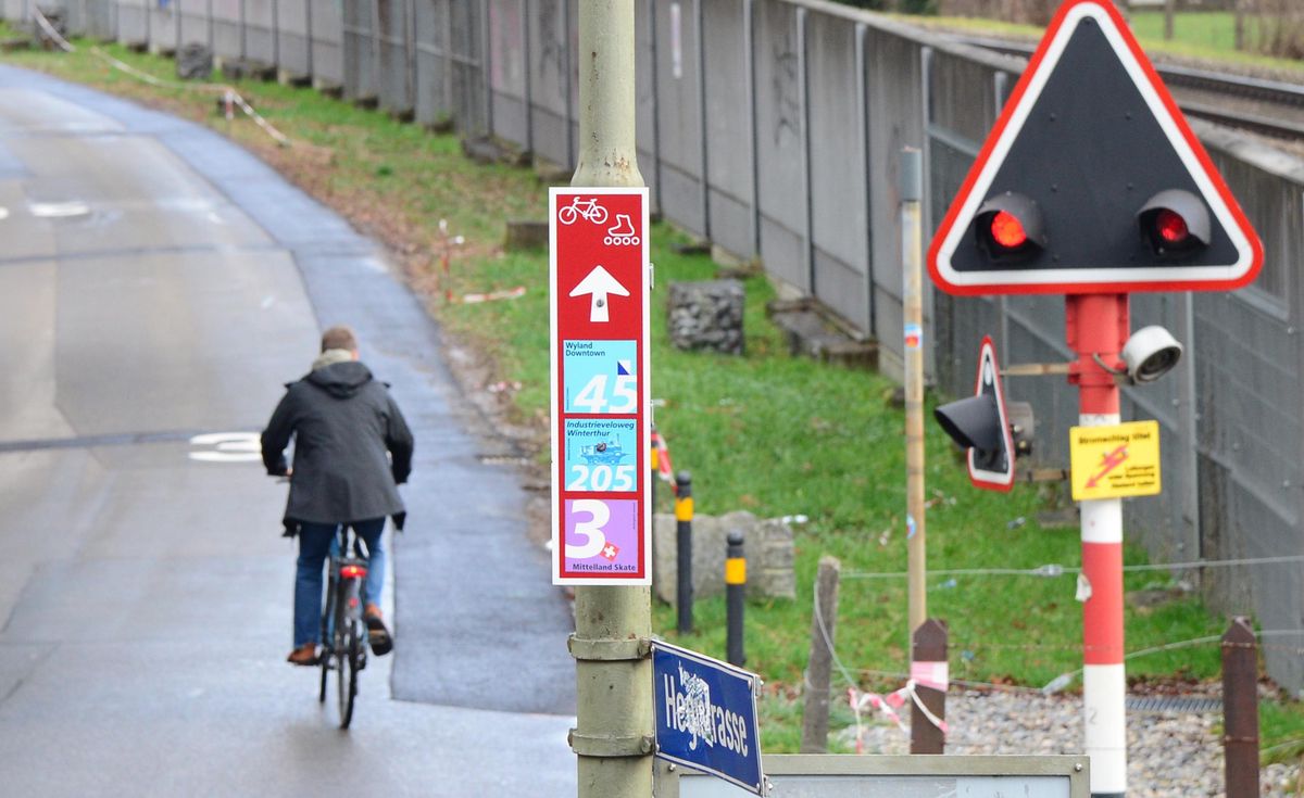 Fahrradfahrer auf dem Veloweg an der Hegistrasse in Winterthur, neben einem Verkehrsschild mit Wegweisern und einem Andreaskreuz. Foto: Marc Dahinden, 05.01.2022