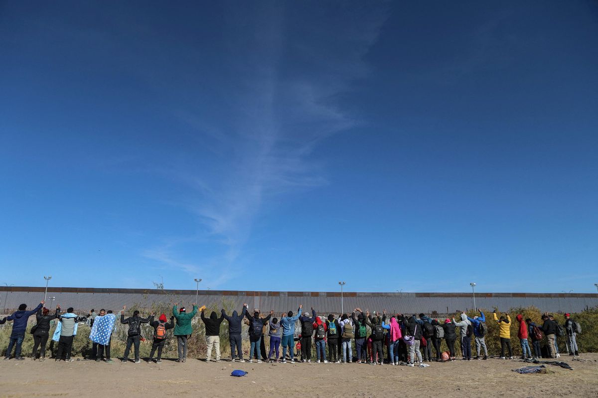 Migrants pray as they approach a wire fence guarded by the Texas National Guard in Ciudad Juarez, Chihuahua state, Mexico, on December 18, 2024, in their attempt to cross into the United States to seek asylum on International Migrants Day. (Photo by Herika Martinez / AFP)