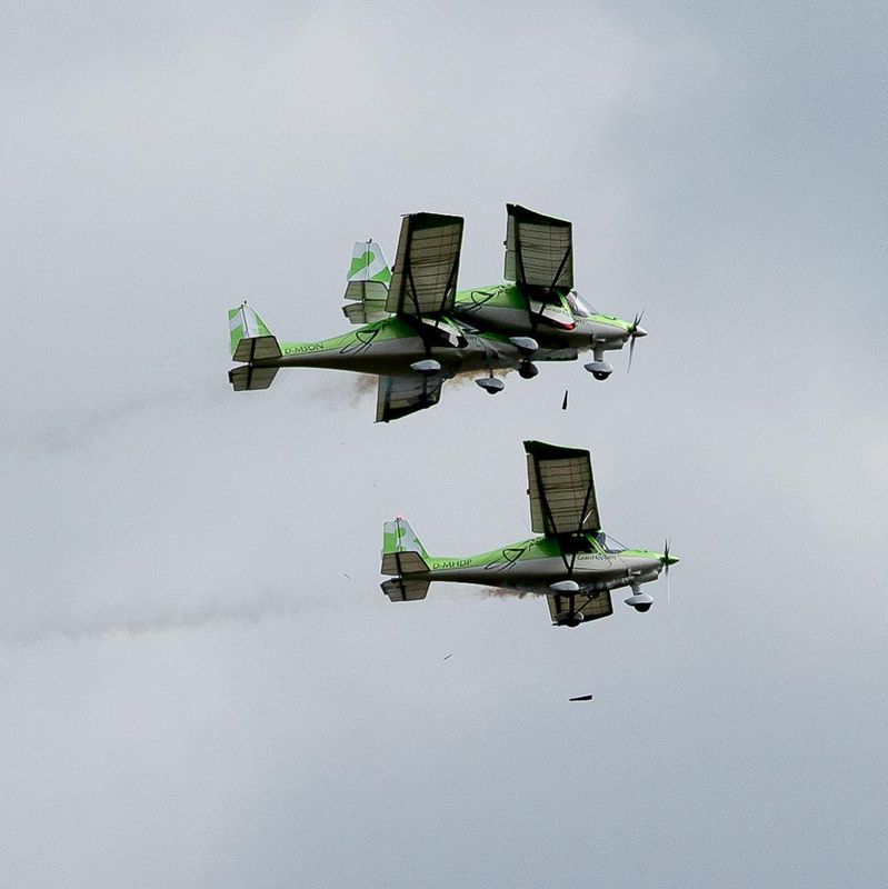 Zwei Flugzeuge fliegen synchron am Himmel, beide in grüner Farbe lackiert, mit Rauchspuren hinter sich. Zwei Flugzeuge fliegen synchron am Himmel, beide in grüner Farbe lackiert, mit Rauchspuren hinter sich.