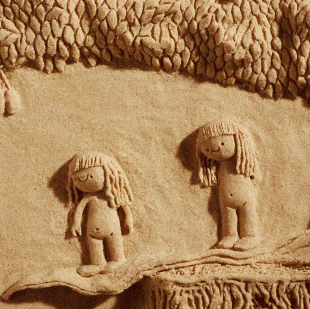Deux figures enfantines sculptées dans le sable se tiennent sous un arbre dans une scène artistique.