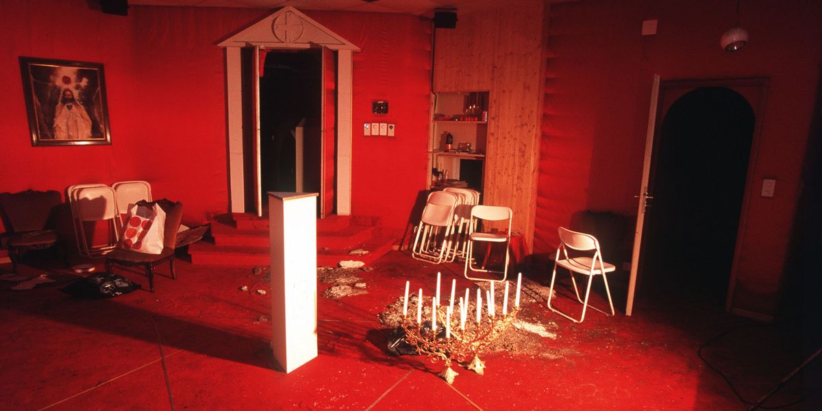 Salle rouge à Cheiry avec autel, chaises blanches et bougies après le suicide de la secte du Temple solaire.