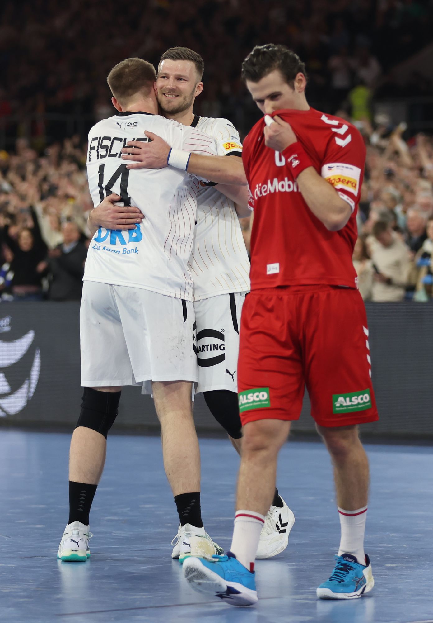 DUESSELDORF, GERMANY - JANUARY 10: Justus Fischer of Germany  celebrates as a Swiss player looks dejected after the Men's EHF Euro 2024 preliminary round match between Germany and Switzerland at Merkur Spiel-Arena on January 10, 2024 in Duesseldorf, Germany. (Photo by Lars Baron/Getty Images)