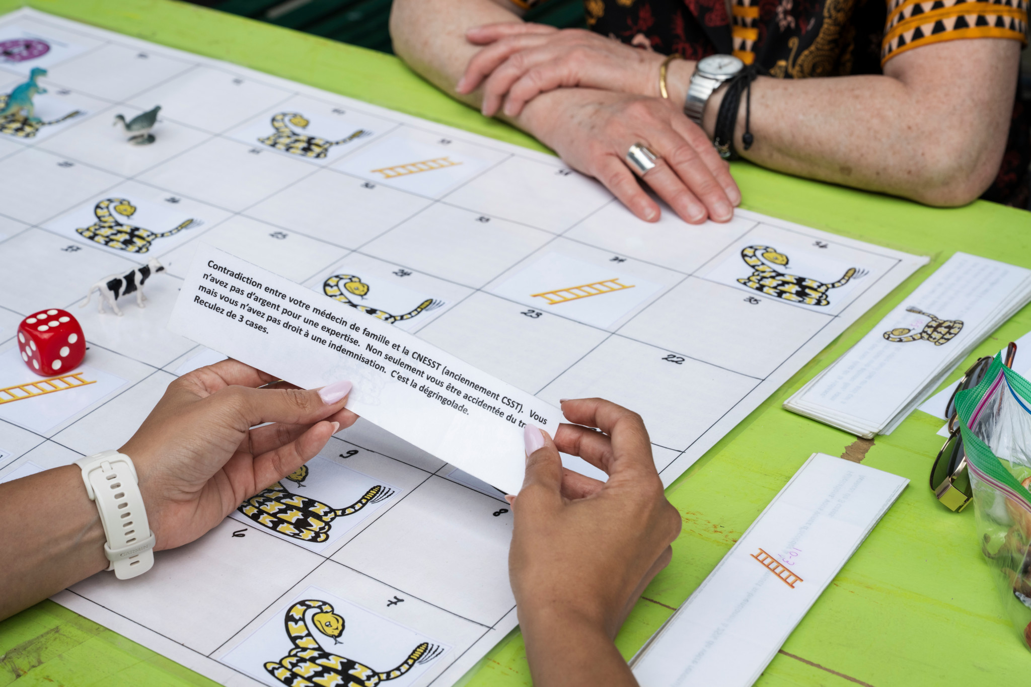 Participantes à une rencontre internationale de femmes sans-abri à Lausanne jouant à un jeu de société pédagogique sur une table verte.