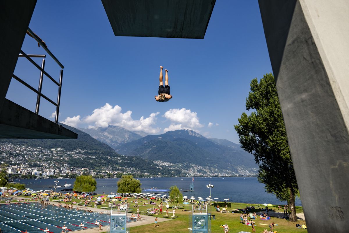 Une personne saute depuis le plongeoir dans le piscine du Lido lors d'une chaude journee d'ete le samedi 10 aout 2024 a Locarno. La vague de chaleur au Sud des Alpes se renforce nettement. Des temperatures caniculaires sont attendues au Tessin. (KEYSTONE/Jean-Christophe Bott)