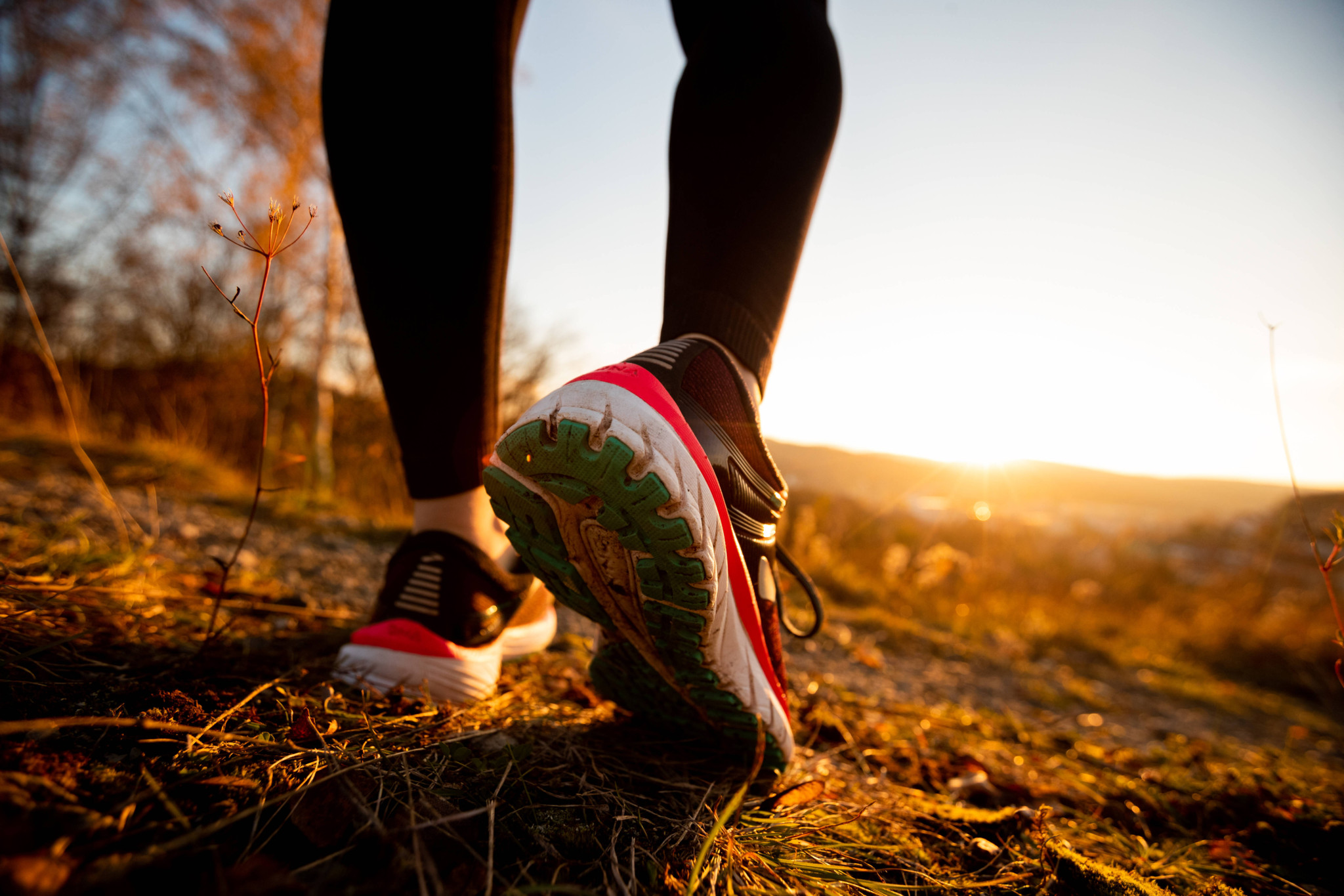 Frau joggt in herbstlicher Landschaft bei Sonnenuntergang, nahe Eisenach, Thüringen.