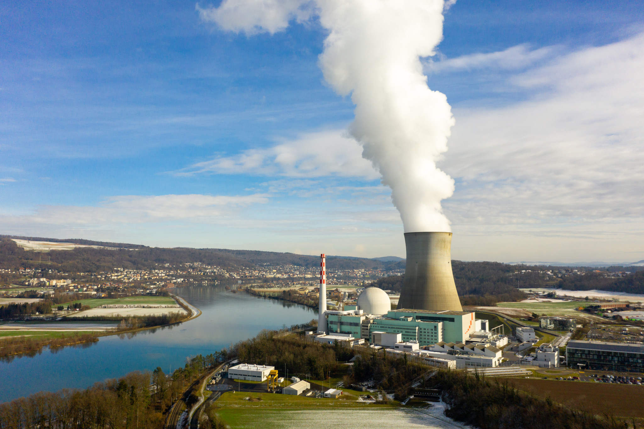 Luftaufnahme des Kernkraftwerks Gösgen in der Gemeinde Däniken, Solothurn, mit Dampfwolke aus dem Kühlturm und Fluss Aare im Hintergrund.