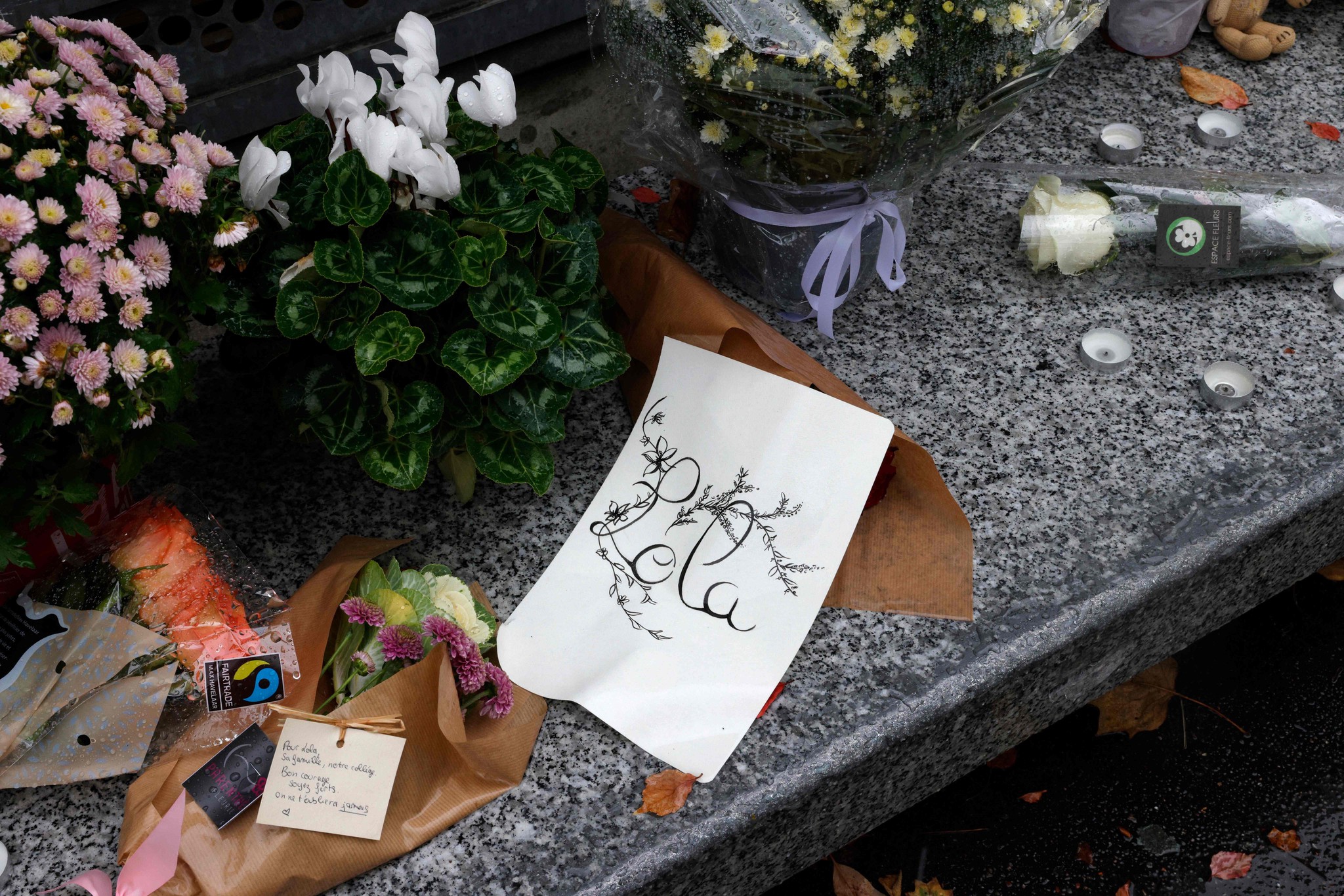A photograph shows flowers displayed outside the middle school Georges Brassens in Paris on October 17, 2022, where studied a 12-year-old schoolgirl, named Lola, three days after her body was discovered in a trunk. - A woman and a man are presented to an examining magistrate on October 17, 2022 in Paris with a view to an indictment for murder and rape with acts of torture and barbarism. (Photo by Geoffroy Van der Hasselt / AFP)