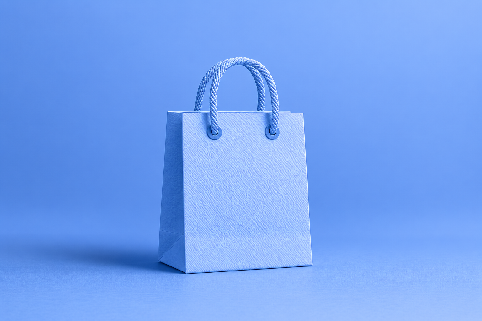 Sac de shopping en papier bleu avec poignées torsadées sur fond bleu uni Sac de shopping en papier bleu avec poignées torsadées sur fond bleu uni