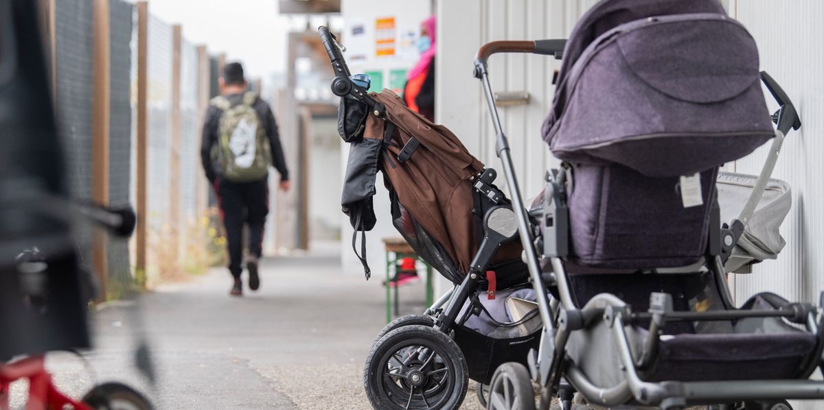 Poussettes alignées à l'extérieur d'un centre de retour pour demandeurs d'asile déboutés à Biel-Bözingen, avec des personnes à l'arrière-plan marchant sur un chemin.