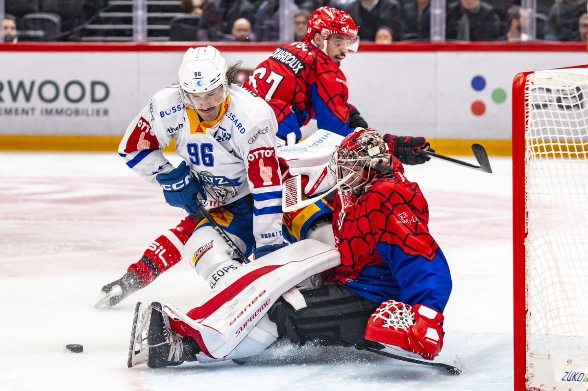 Joueur de l'EV Zug, en blanc, lutte pour le puck avec le gardien du Lausanne HC, en rouge, lors d'un match de hockey à la Vaudoise arena.
