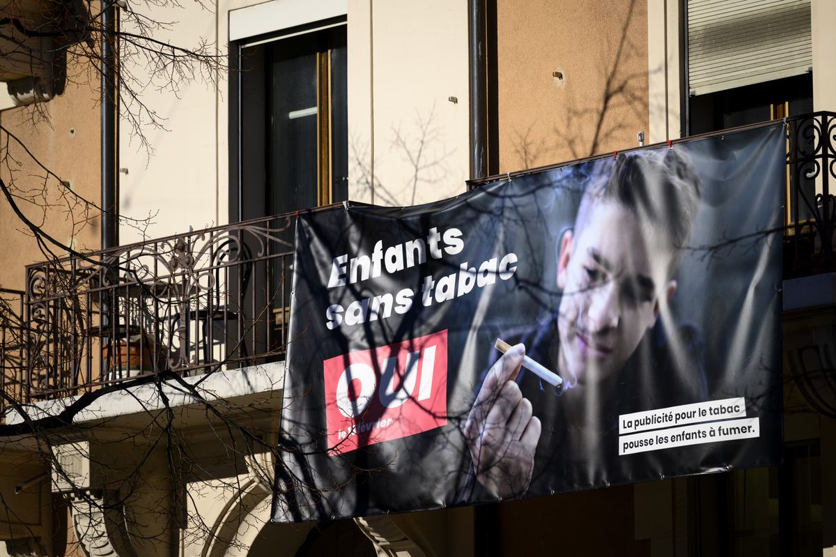Une banderole representant une affiche "Enfants sans tabac" incitant a voter oui a l'interdiction de la publicite pour le tabac qui pousse les enfants a fumer est photographiee ce mardi 8 fevrier 2022 a Lausanne. Le 13 fevrier prochain la population suisse va se prononcer lors d'une votation sur l' initiative populaire "Oui a la protection des enfants et des jeunes contre la publicite pour le tabac". (KEYSTONE/Laurent Gillieron)