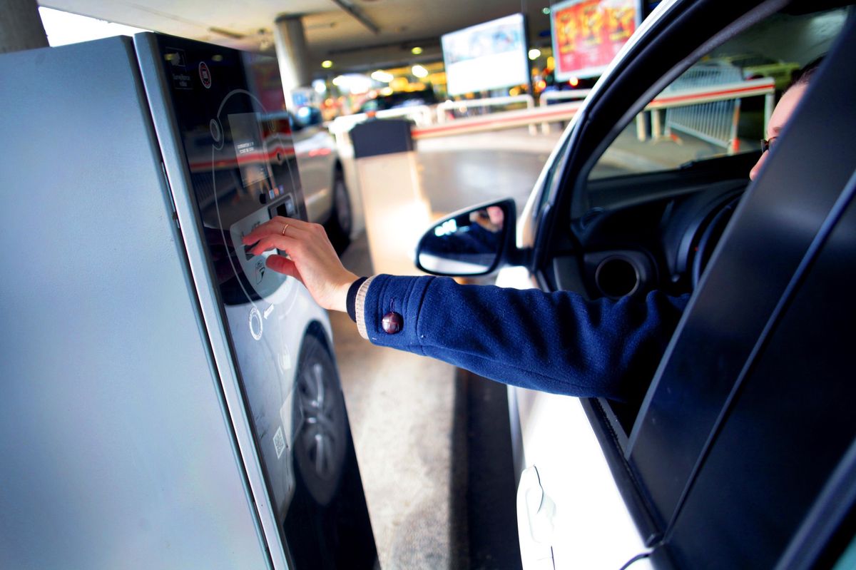 Système de paiement automatique dans un parking de Genève, inauguré pour éviter les arnaques, avec une personne interagissant avec la machine.