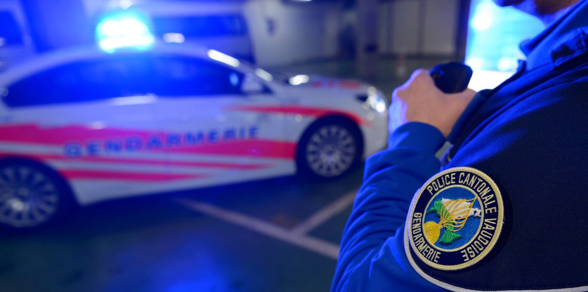 Un gendarme de la Police cantonale vaudoise près d'une voiture de police avec des lumières bleues allumées dans un garage à Cugy, Vaud, le 3 novembre 2015.