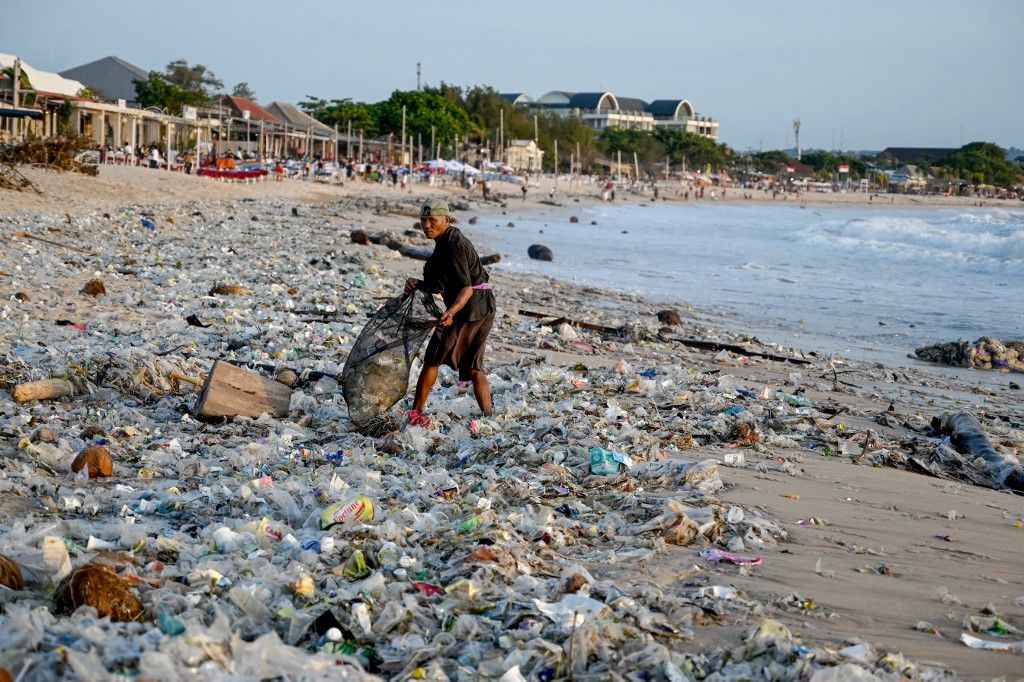 Un homme ramasse des déchets sur la plage de Kedonganan à Bali, le 19 mars 2024.