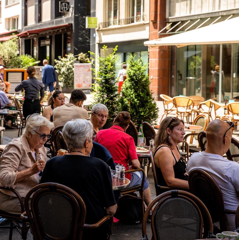 Strassencafés in der Steinenvorstadt Basel mit Menschen, die an Tischen im Freien sitzen und die Umgebung geniessen.