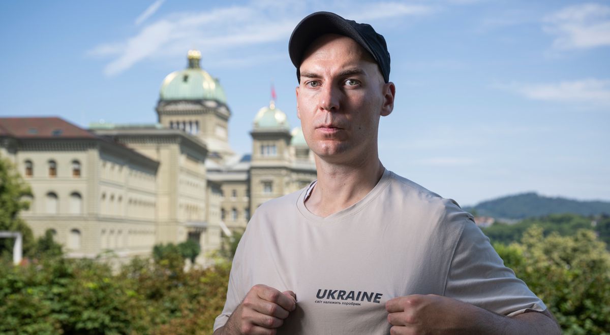 Jona Neidhart, un Suisse qui a combattu en Ukraine, posant devant le Palais fédéral à Berne le 19 juillet 2024. Il porte un t-shirt avec l'inscription 'UKRAINE'.