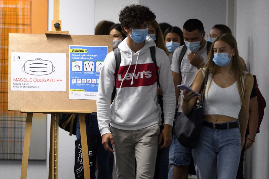 Des eleves, portant un masque marchent dans les couloirs, a cote d'un panneau masque obligatoire, apres un cours du Gymnase de Provence le jour de la rentree scolaire des etudiants vaudois lors de la pandemie de Coronavirus (Covid-19) ce lundi 24 aout 2020 a Lausanne. (KEYSTONE/Laurent Gillieron)