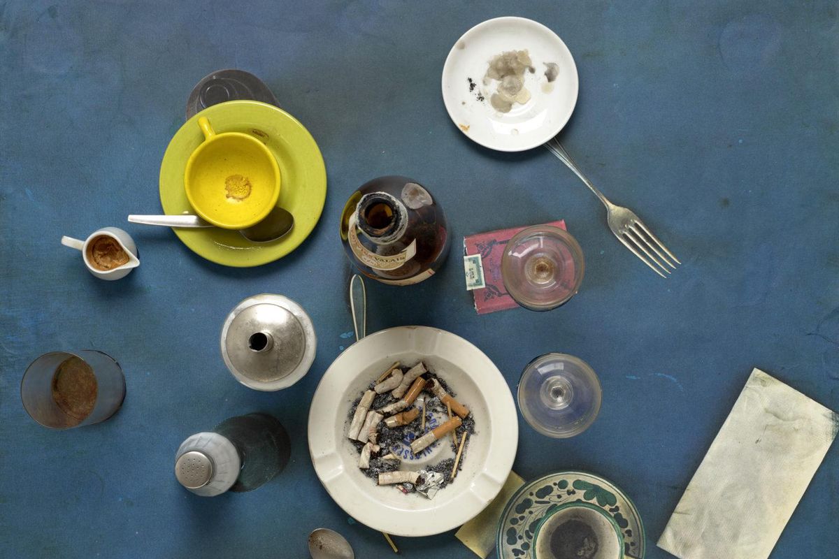 Assemblage artistique de Daniel Spoerri avec divers objets, y compris assiettes, couverts et tasses, disposés sur une photocopie collée.