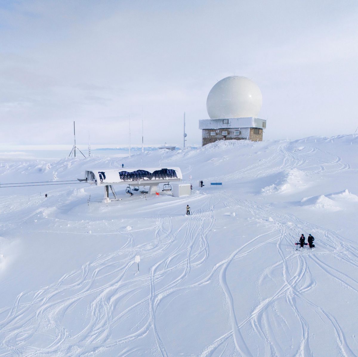 Vue sur le domaine skiable des Dappes à la Dôle avec une poudreuse exceptionnelle, montrant un télésiège et un bâtiment avec un dôme, le 10 janvier 2024.