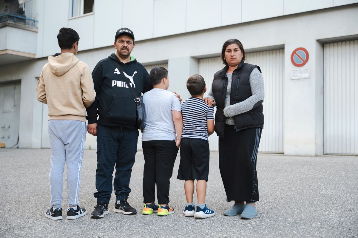 Costel et Adina avec leurs familles devant un bâtiment à Lausanne, après avoir été expulsés de la Borde 47. Deux enfants font face à la caméra, et deux autres leur tournent le dos.